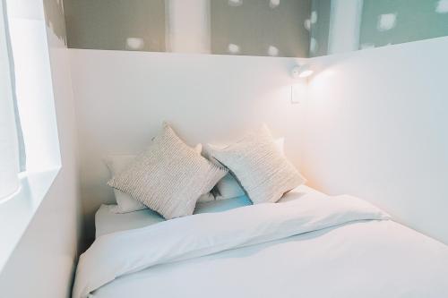 a white bed with pillows on top of it at Of Hotel in Sendai