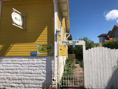 una casa amarilla con una puerta blanca y una valla en Villa Verdi, en Borgholm