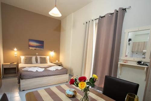 a bedroom with a bed and a table with flowers at Rania Studios in Gouves