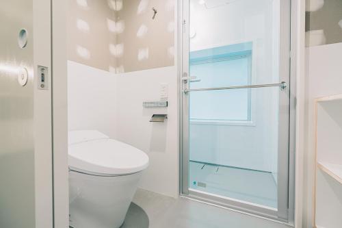 a bathroom with a toilet and a glass shower door at Of Hotel in Sendai