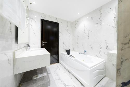 a white bathroom with a sink and a bath tub at Abha Gardn Millennium Hotel in Abha