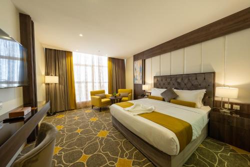 um quarto de hotel com uma cama grande e uma cadeira em Abha Gardn Millennium Hotel em Abha