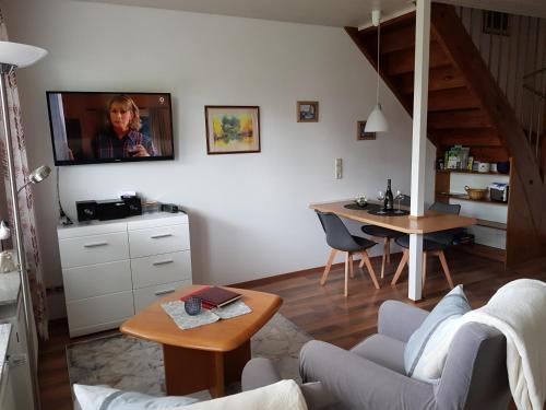 ein Wohnzimmer mit einem Sofa und einem TV an der Wand in der Unterkunft Ferienwohnung Kirschblüte in Billigheim-Ingenheim
