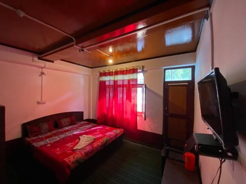a bedroom with a red bed and a tv at Ashiyana Hotel in Kargil