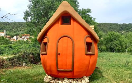 an orange dog house sitting in a field at Krka Magic Pumpkin in Rupe