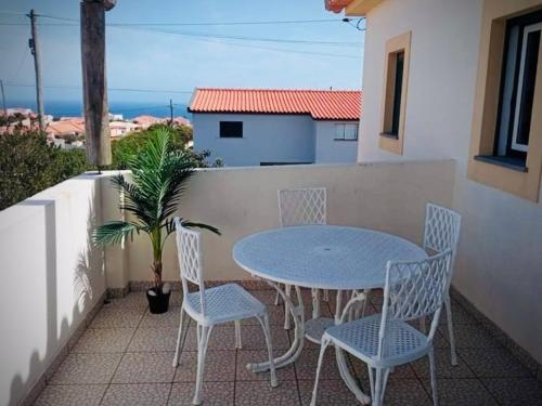 ein Tisch und Stühle auf einem Balkon mit Blick auf das Meer in der Unterkunft Porto Santo Casa Dourada in Porto Santo