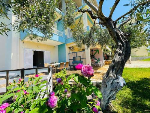 a house with a tree and flowers in the yard at Triantis Apartments in Ligia