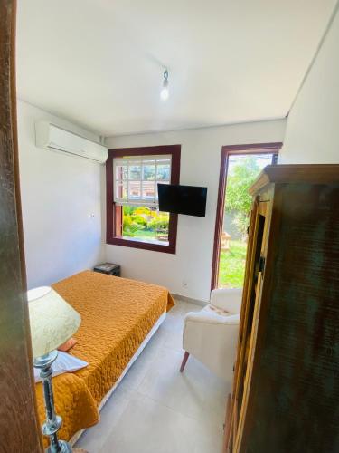 a bedroom with a bed and a tv and a window at POUSADA CHARLOTTE in Tiradentes
