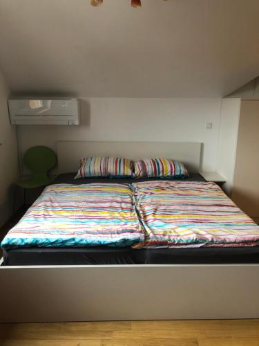 Una cama con una manta de colores en una habitación en Apartma Ajda 2 , Jezerska cesta 65, Kranj, en Kranj