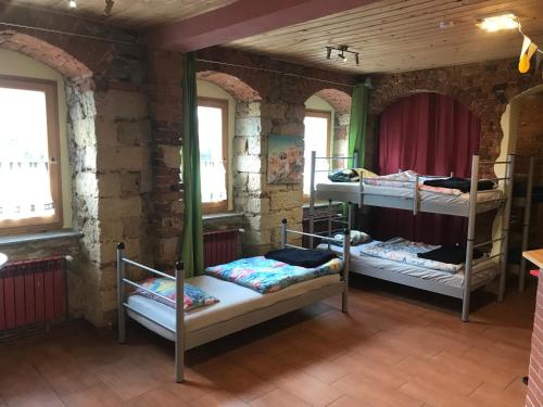 a room with three bunk beds in a brick wall at Hostel Meissen Old Town Bridge in Meißen