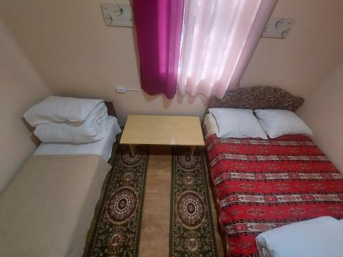 a small room with two beds and a table at RAHAT Guest House & Hostel in Toktogul in Toktogul