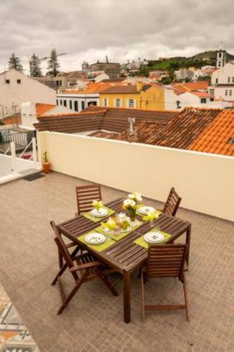 a table and chairs on a balcony with a view of a city at Casa Amarela AL 3030 in Horta