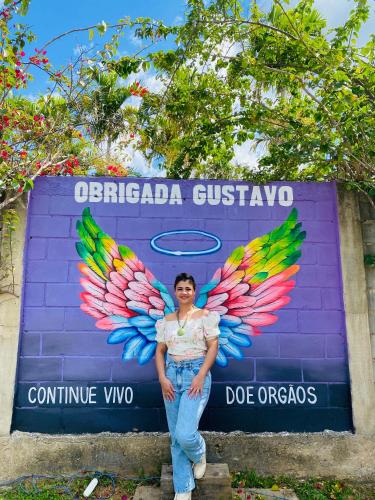 a woman standing in front of a sign with wings at POUSADA CHARLOTTE in Tiradentes
