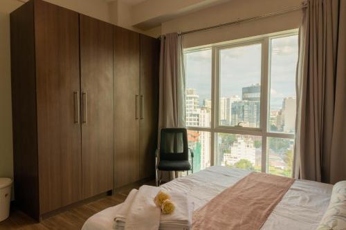 a bedroom with a bed and a large window at Ayala Mall 10mins walk Cebu City Apartment & Pool in Cebu City
