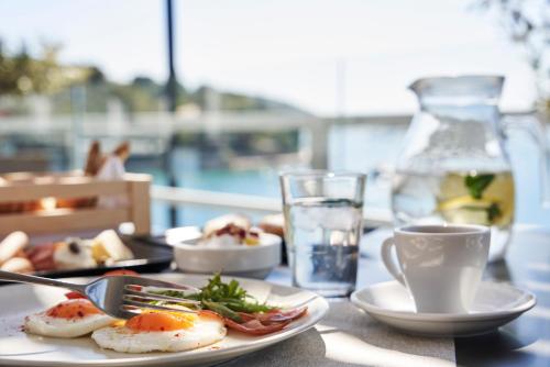 a table with plates of food and a glass of water at Xenia Poros Image Hotel in Poros