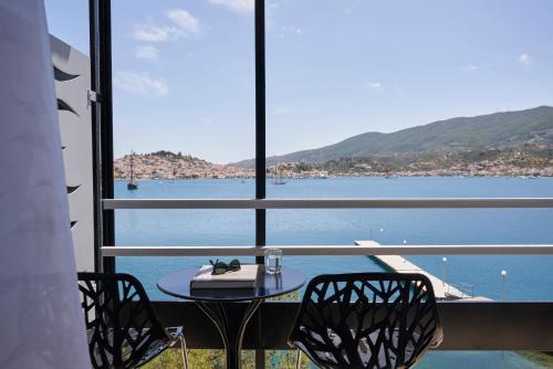 a table and chairs on a balcony with a view of the water at Xenia Poros Image Hotel in Poros