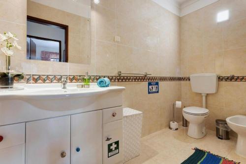 a bathroom with a sink and a toilet and a mirror at Dunas Mar in Alvor