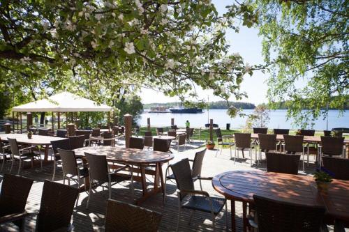a patio with tables and chairs and a view of the water at Hotel Hospitz in Savonlinna
