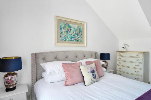 um quarto com uma cama com lençóis brancos e almofadas em Craig Leith Apartment em Alloa