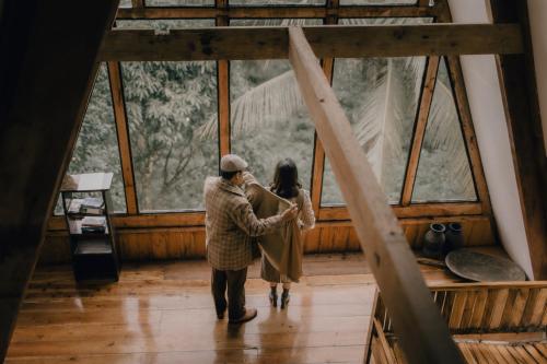 a man and a woman standing in front of a window at Camiguin Volcano Houses - A-Frame house in Mambajao