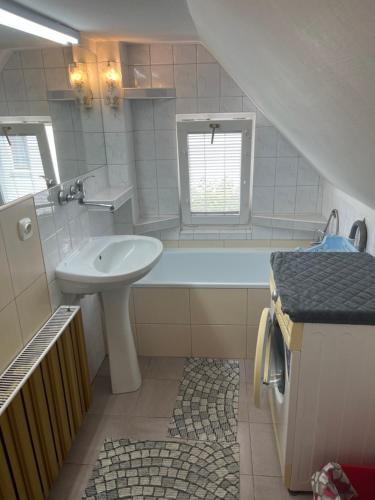 a white bathroom with a sink and a bath tub at Pokoje Gościnne Agata & Mikołaj in Władysławowo