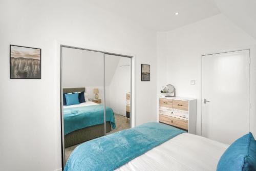 ein weißes Schlafzimmer mit einem Bett und einem Spiegel in der Unterkunft Myreton Hill Apartment in Alloa