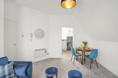 a living room with a table and blue chairs at Myreton Hill Apartment in Alloa