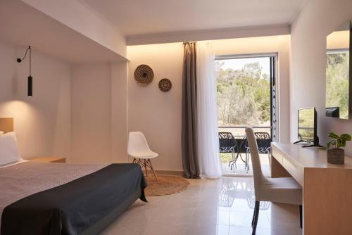 a bedroom with a bed and a desk and a window at Xenia Poros Image Hotel in Poros