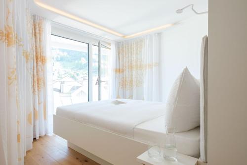 a white bedroom with a bed and a large window at Neuro Campus Hotel in Vitznau
