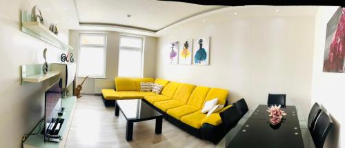 a living room with a yellow couch and a table at Best City Apartment in Hannover
