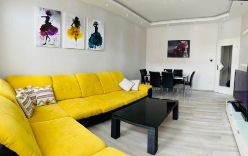 - un salon avec un canapé jaune et une table dans l'établissement Best City Apartment, à Hanovre