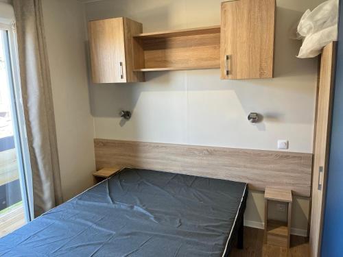 a small room with a bed and wooden cabinets at Camping De Collignon in Cherbourg en Cotentin