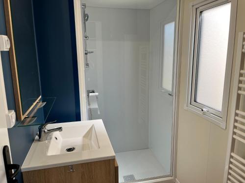 een badkamer met een witte wastafel en een douche bij Camping De Collignon in Cherbourg en Cotentin