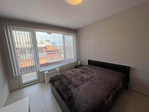 a bedroom with a bed and a large window at Valemar Apartments in Pomorie