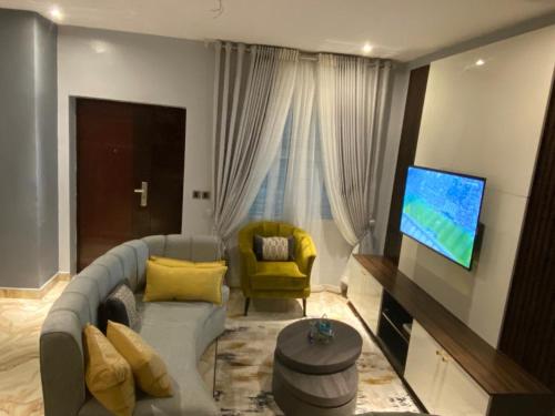 a living room with a couch and a flat screen tv at Blue Bell Suites in Lekki