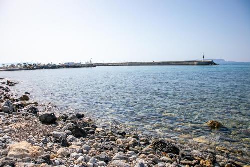 a rocky beach with a pier in the water at Rania Studios in Gouves