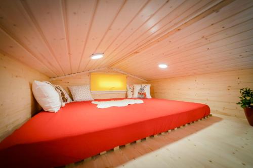 1 cama grande de color rojo en una habitación de madera en Tiny House - Birne, en Wald