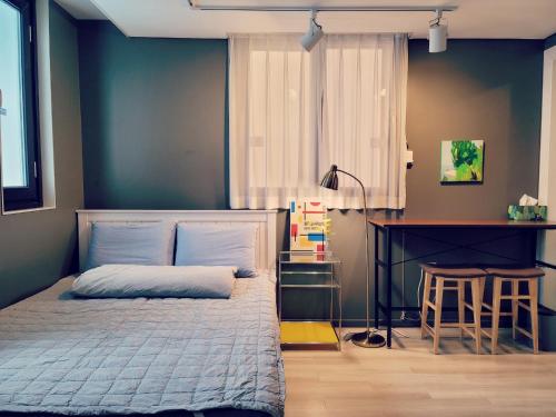 a bedroom with a bed and a desk and a table at Picasso Guesthouse in Mokpo