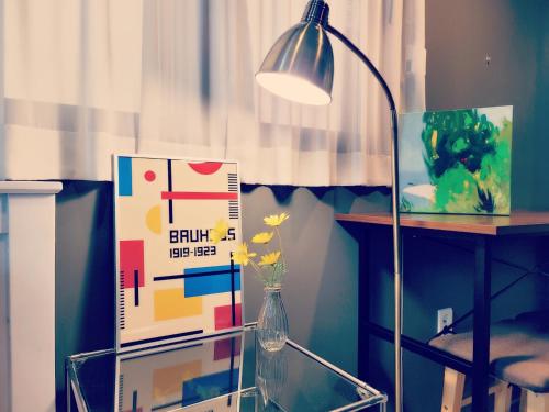a lamp sitting next to a table and a vase with flowers at Picasso Guesthouse in Mokpo