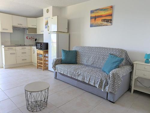 un salon avec un canapé et une cuisine dans l'établissement Appartement proche port et mer avec wifi et climatisation, au Cap d'Agde