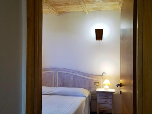 a small bedroom with a bed and a lamp on a table at La Corte degli Ulivi - Albergo Rurale in Tresnuraghes