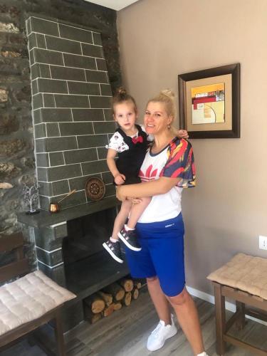a woman holding a child in front of a fireplace at Vila Culli in Përmet