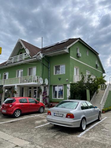 two cars parked in a parking lot in front of a house at Pensiunea Simina in Caransebeş