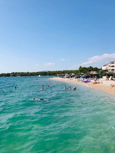 a group of people in the water at a beach at Apartman AS in Pirovac