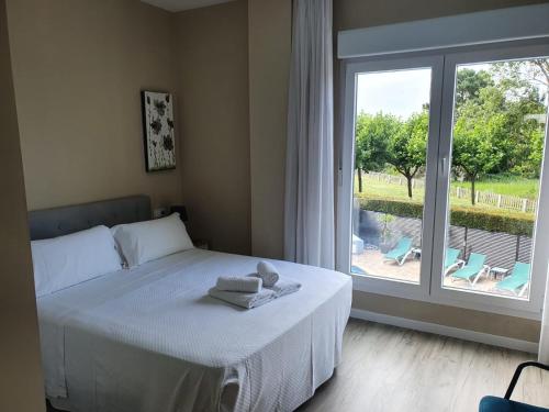 sypialnia z łóżkiem z ręcznikami i oknem w obiekcie Apartamentos Dunamar w mieście Noalla