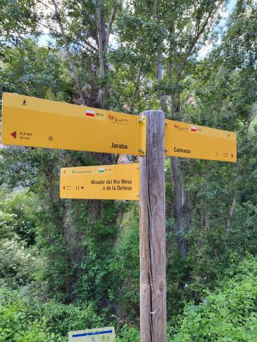 a yellow sign with arrows on a wooden pole at Casa Rural Reyes in Nuévalos