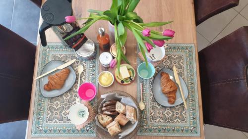 une table avec des assiettes de nourriture et un vase avec des fleurs dans l'établissement Le cottage de Lily, à Bonnemain