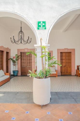a lobby with a large pillar with plants in it at Hotel Catedral in Cuernavaca
