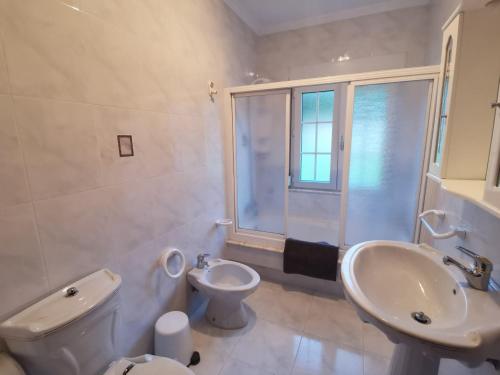 a white bathroom with a sink and a toilet at Casa da Pioxa in Camariñas