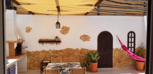a room with a table and a stone wall at Estrelinha da Fuzeta in Fuzeta
